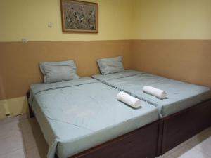 duas camas sentadas uma ao lado da outra num quarto em PROMOSIA GUEST HOUSE em Surabaya