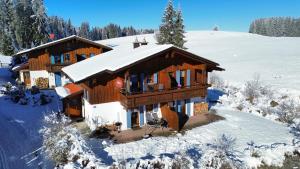 uma casa de madeira na neve com neve em Feriendorf Via Claudia Haus 100 Dominique em Lechbruck