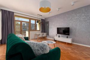 a living room with a green couch and a tv at Zdrowa Esthetic Apartment in Wrocław