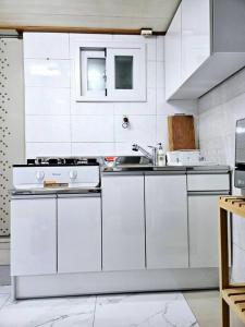 - une cuisine blanche avec des placards blancs et un évier dans l'établissement [New]Seongsu/Konkuk U/PoguniStay, à Séoul