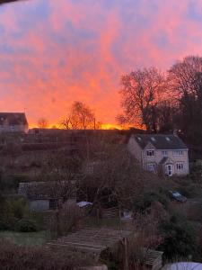 um pôr-do-sol sobre uma aldeia com casas e árvores em Dove Cottage em Bisley