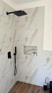uma casa de banho com paredes em mármore branco e um chuveiro em CURRILA STAYS em Durrës