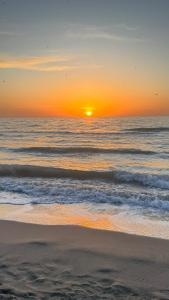 um pôr-do-sol numa praia com o oceano em CURRILA STAYS em Durrës