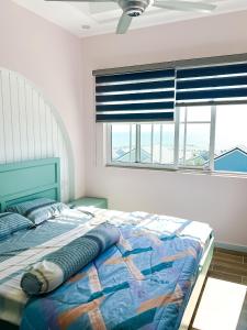 een bed in een slaapkamer met een raam met jaloezieën bij Kat House Novaworld Phan Thiết in Bình Tú