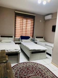 um quarto com 3 camas, uma janela e um tapete em ObodHotel em Dushanbe