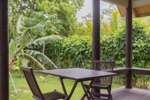 um alpendre em madeira com uma mesa e 2 cadeiras em Bella Beach Lodge em Rarotonga