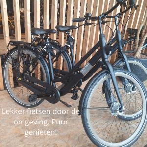 a black bike parked next to a wooden fence at B&B De NieuwenHof 'De Voorkamer' in Melderslo