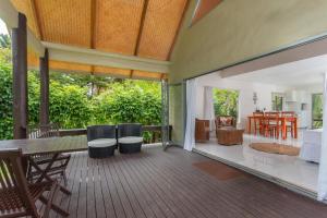 an open deck with a table and chairs and a living room at Bella Beach Lodge in Rarotonga