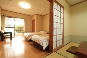 een slaapkamer met 2 bedden en een raam bij ニュー筑水荘 in Ukiha
