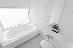 La salle de bains blanche est pourvue d'une baignoire et d'une fenêtre. dans l'établissement MARSOL C,S,Beach hotel - Vacation STAY 73619v, à Chigasaki