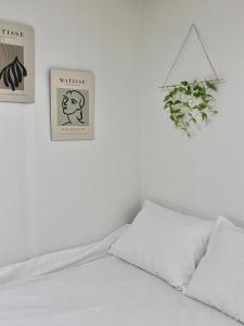 łóżko z dwoma plakatami na ścianie i roślina w obiekcie Ulsan stay w mieście Ulsan