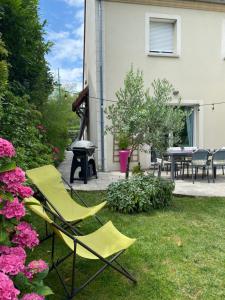 dos sillas y una mesa en un patio con flores en EXIGEHOME - Grande maison - 140m² - spacieuse et confortable, en Jouy-en-Josas