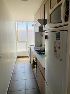 a kitchen with a white refrigerator and a window at Alto mar II in Viña del Mar
