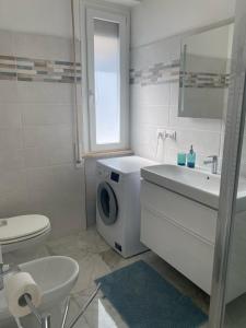 ein weißes Badezimmer mit einer Waschmaschine und einem Waschbecken in der Unterkunft La tua casa sul mare in Sestri Levante