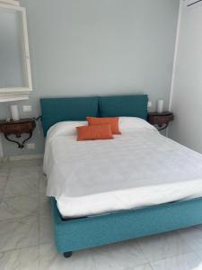 ein blaues Bett mit zwei orangenen Kissen darauf in der Unterkunft La tua casa sul mare in Sestri Levante