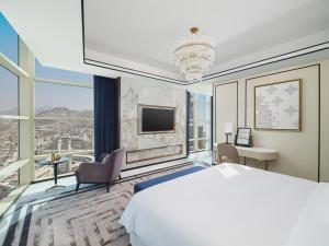 a bedroom with a large bed and a large window at Address Jabal Omar Makkah in Mecca