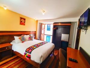 Dormitorio con cama, escritorio y TV en Posada San Blas en Cuzco