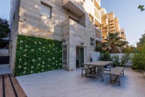 patio z 2 ławkami obok budynku w obiekcie Rothschild Modern Apartment with a Pool w Tel Awiwie
