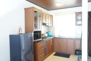 cocina con armarios de madera y nevera de acero inoxidable en Lake infinity Penthouse en Nuwara Eliya