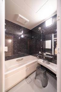 a bathroom with a tub and a sink and a mirror at UTAKATA HOTEL HIMEJI in Himeji