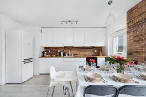 a white kitchen with a table and white cabinets at Bella Casa Premium Apartment - 104 Kobierzynska in Krakow