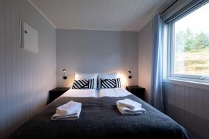 1 dormitorio con 1 cama con 2 toallas en Lofotlove Apartments - Modern and Comfy Apartments Close To Nature en Sørvågen