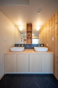 due lavandini in un ampio bagno con pareti in legno di UTAKATA HOTEL HIMEJI a Himeji