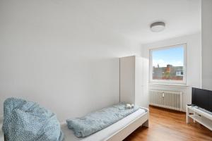 Cette chambre blanche dispose d'un canapé et d'une télévision. dans l'établissement Nice Apartment in Bremerhaven, à Bremerhaven