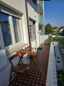 un patio con 2 sillas y una mesa en el balcón en APPARTAMENTO STELLA MARE, en Lignano Sabbiadoro