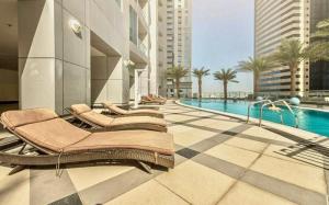 een hotel met een zwembad en ligstoelen naast een gebouw bij Torch Tower,Dubai Marina - 1BR Apartment - Allsopp&Allsopp in Dubai