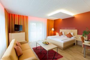 a room with a bed and a couch and a tv at Hotel Süd Graz in Graz