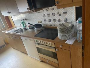 een keuken met een wastafel, een fornuis en borden bij Chambre privé 1 in Trier