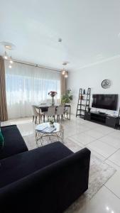 a living room with a black couch and a table at Two Continents Holiday Homes - Marvelous Marina Apartment in Dubai
