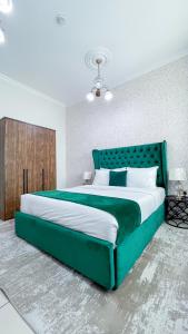 a large green bed in a white bedroom at Two Continents Holiday Homes - Marvelous Marina Apartment in Dubai