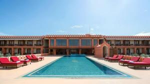 a resort with a swimming pool with red chairs and a building at Royal Palace Hotel in Nyoungoo