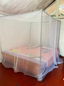 a bed covered in mosquito net in a room at Rainbow Village Cabanas in Arugam Bay