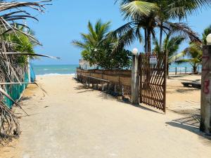 a gate on a beach with palm trees and the ocean at Rainbow Village Cabanas in Arugam Bay