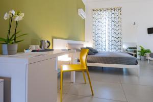 1 dormitorio con 1 cama y escritorio con silla amarilla en Suite Inn Catania, en Catania