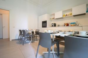 a dining room with tables and chairs and a kitchen at Suite Inn Catania in Catania