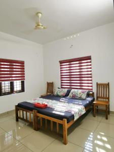 a bedroom with a bed and two chairs in it at TROPICAL STORIES in Varkala