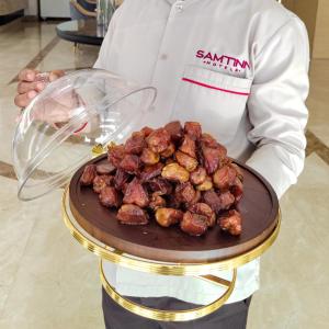 um chef que segura um prato de comida numa mesa em Samt Inn Hotel em Riade