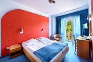 a bedroom with a bed with a red wall at Hotel Négy Évszak in Hajdúszoboszló