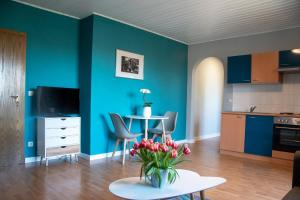 a living room with blue walls and a table with flowers at Ferienwohnung Maintalblick in Eltmann