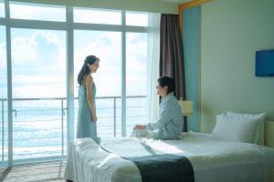 a woman standing next to a bed in a hotel room at Shimoda Prince Hotel in Shimoda
