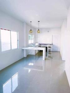 cocina blanca con mesa y algunas ventanas en Minimalism Pool Villa, en Thap Sakae
