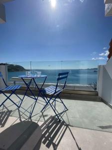 una mesa y sillas en un balcón con vistas al océano en Charaki Sea Breeze Modern Studio with Balcony en Haraki