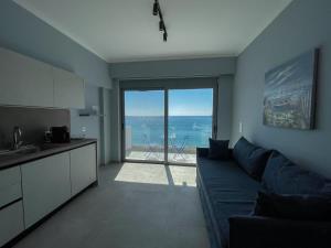 a living room with a blue couch and a view of the ocean at Charaki Sea Breeze Modern Studio with Balcony in Haraki