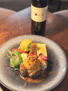 a plate of food on a table with a bottle of wine at Hiša Aleš in Kranj