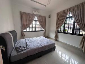 a bedroom with a bed and two large windows at Pelangi Indah 8 Rooms Corner Pool Table in Ulu Tiram