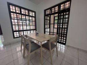 una mesa de madera y sillas en una habitación con ventanas en Pelangi Indah 8 Rooms Corner Pool Table en Ulu Tiram